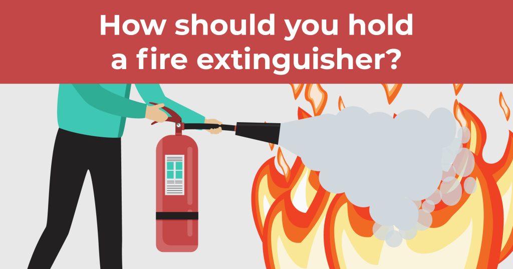 How should you hold a fire extinguisher